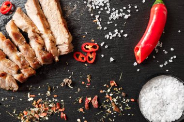 Tavada pişirilmiş domuz eti ve arka planda bulunan baharatlarla dilimlenmiş.