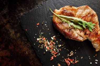 Koyu taşlı arka planda baharatlı kızarmış domuz eti.