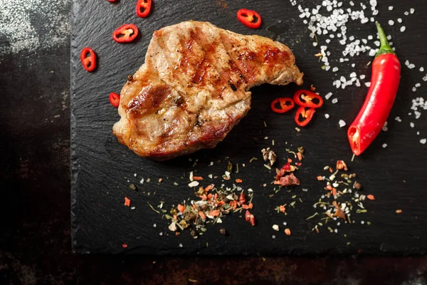 Koyu taşlı arka planda baharatlı kızarmış domuz eti.
