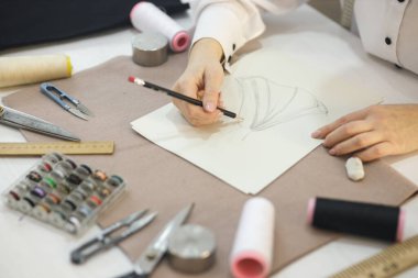 Dikiş dikmek için geleceğin elbisesini çiziyor.