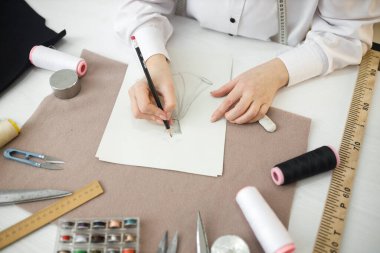 Dikiş dikmek için geleceğin elbisesini çiziyor.