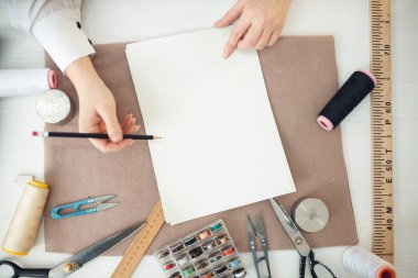 Dikiş dikmek için geleceğin elbisesini çiziyor.