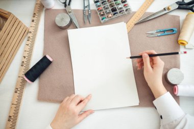 Dikiş dikmek için geleceğin elbisesini çiziyor.