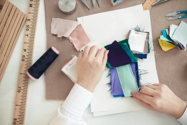 Terzi elbise dikmek için kumaş numunesi seçiyor.