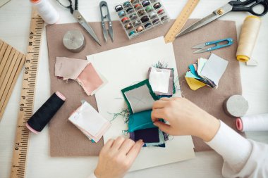 Terzi elbise dikmek için kumaş numunesi seçiyor.