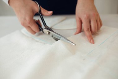 Kapatın. Kadın terzi, terziden aldığı tebeşirle yaptığı elbisenin kalıbını belirlemek için bir rulo kumaş kesiyor..
