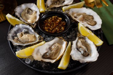 open fresh oysters on a metal plate in ice on a concrete background