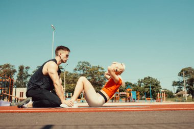 Genç çift yoga minderinde karın kaslarını çalıştırıyor.