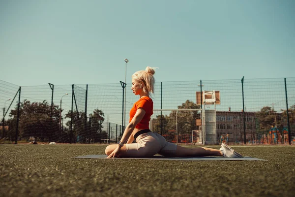 Piękna Blondynka Robi Rozciąganie Trawniku Boiska Piłki Nożnej — Zdjęcie stockowe