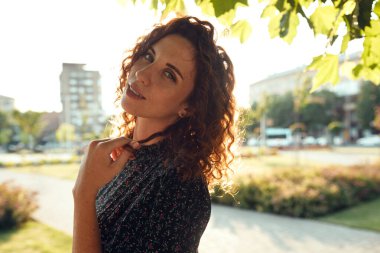 Çekici kızıl saçlı, çilli ve güzel yüzlü bir kızın portreleri. Kız şehir merkezinde kameraya poz veriyor. Harika bir ruh hali ve tatlı bir gülümsemesi var.