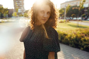 Çekici kızıl saçlı, çilli ve güzel yüzlü bir kızın portreleri. Kız şehir merkezinde kameraya poz veriyor. Harika bir ruh hali ve tatlı bir gülümsemesi var.