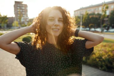 Çekici kızıl saçlı, çilli ve güzel yüzlü bir kızın portreleri. Kız şehir merkezinde kameraya poz veriyor. Harika bir ruh hali ve tatlı bir gülümsemesi var.