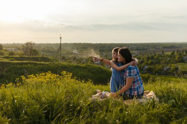 Gün batımında oturan annesi ile küçük şirin kız