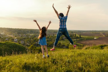 Anne ve kızı, günbatımında sıçrama