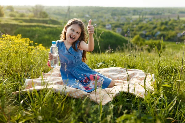 Girl in grass with plastic water bottle — Stock Photo, Image