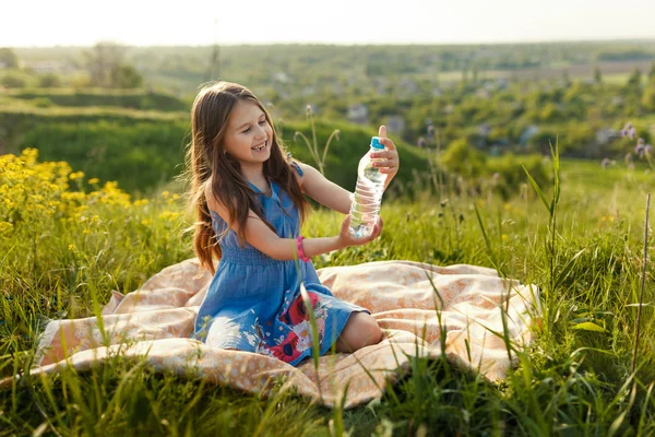 Chica en la hierba con botella de agua de plástico — Foto de Stock