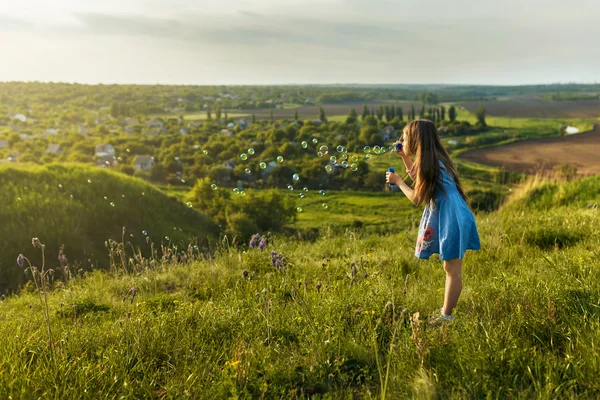 Cute little girl is blowing a soap bubbles — Stock Photo, Image