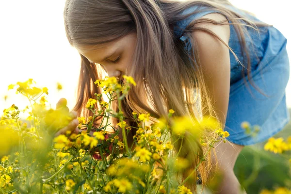 Kleines Mädchen, das eine gelbe Blume riecht — Stockfoto