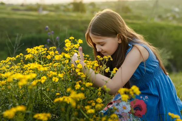 Niña oliendo una flor amarilla — Foto de Stock