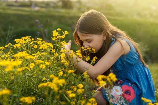 little girl smelling a yellow flower