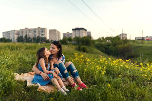 Маленька мила дівчинка з матір'ю сидить на заході сонця — стокове фото