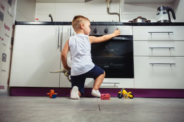 गॅस स्टोव्हसह स्वयंपाकघरात खेळत मुलगा . — स्टॉक फोटो, इमेज