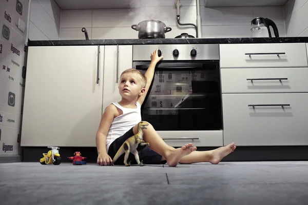 Kind spielt in der Küche mit Gasherd. — Stockfoto