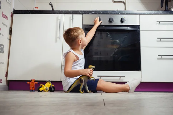 Kind spielt in der Küche mit Gasherd. Stockfoto