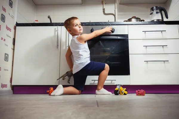 Kind spielt in der Küche mit Gasherd. Stockbild