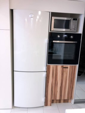 Modern mutfak alanı, ahşap zemin, modern buzdolabı ve aletler.