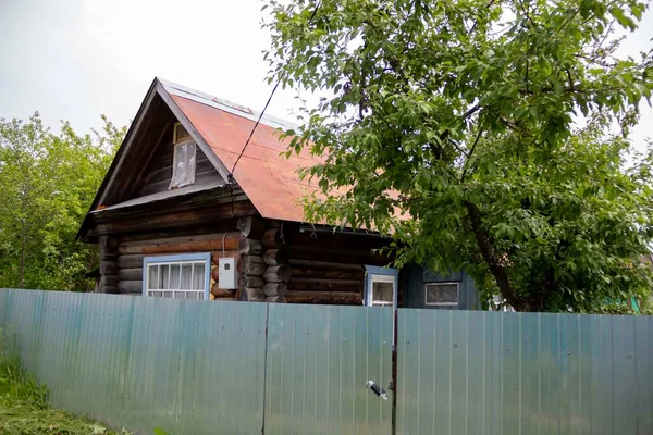 Casa de madeira velha residencial atrás de uma cerca alta de ferro — Fotografia de Stock