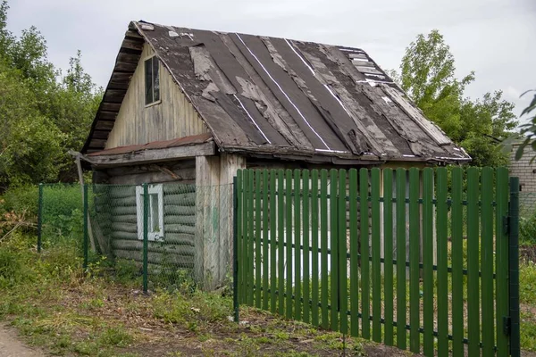 Demir yüksek çitlerin arkasında eski ahşap bir ev. — Stok fotoğraf