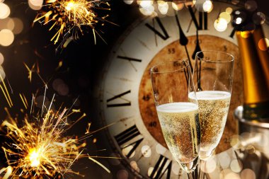 Festive New Years background with sparklers and champagne in front of a clock counting down to midnight with sparkling bokeh on darkness clipart