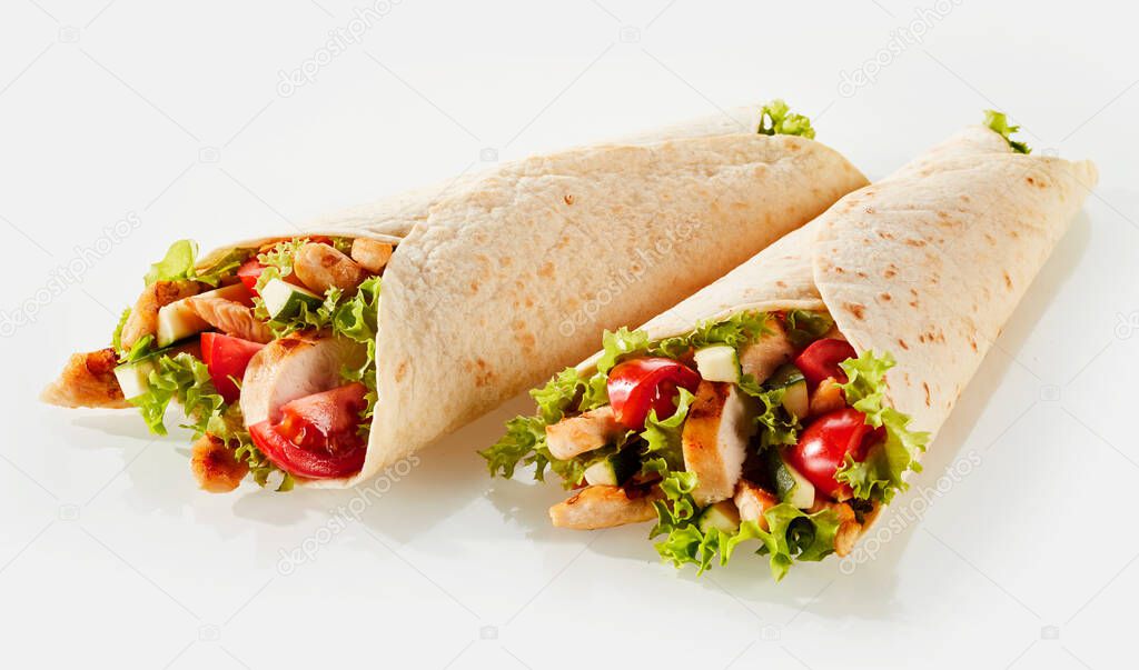 Two fresh tortilla wraps with vegetable filling and chicken against white background