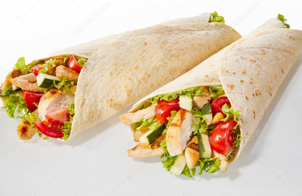 Two chicken and salad wraps on studio background