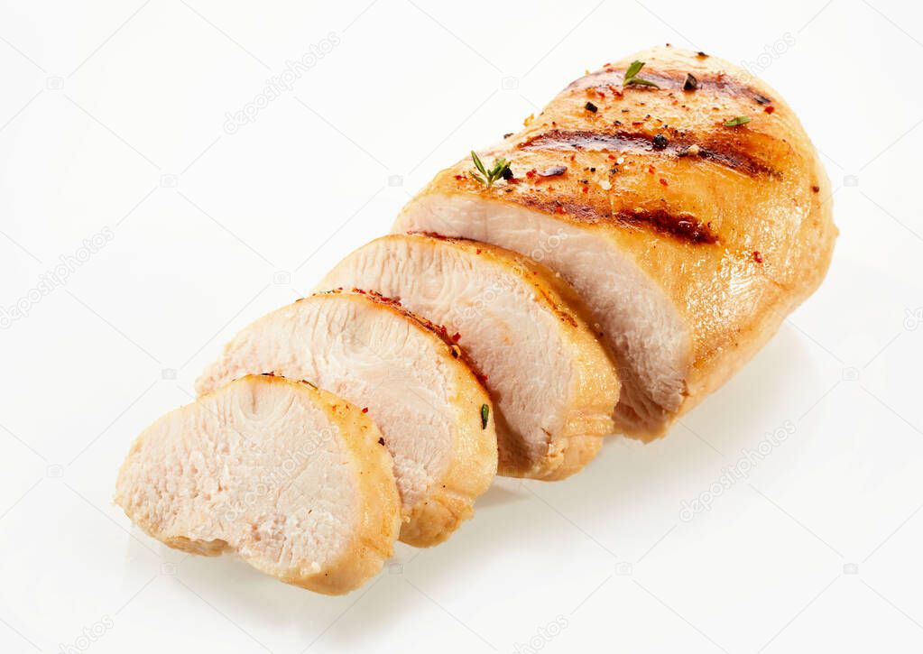 A close up of a golden, grilled, sliced chicken breast with a white background and copy space.