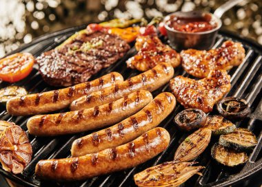 Delicious summer BBQ grilling over the fire with sausages , chicken wings, steak, mushrooms, tomato, baby marrow, garlic and onion clipart