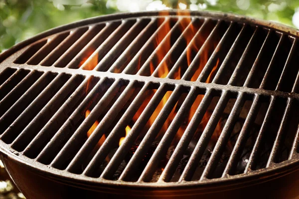 在一个便携式的夏季烧烤中 在炽热的煤块上点燃着篝火 炉顶上有一个空烤架 等待着食物的摆放 — 图库照片