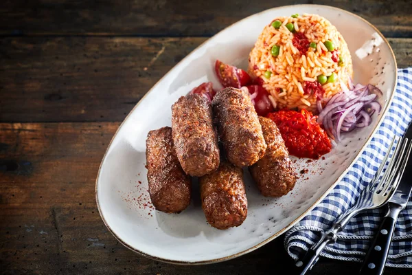 传统的切瓦皮 Cevapcici 或碾碎牛肉片 与味道鲜美的米饭一起 用椭圆形的长盘在乡村木柴上食用 — 图库照片