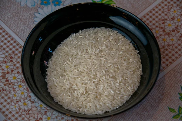 Рис в сыром виде в черной тарелке. — стоковое фото