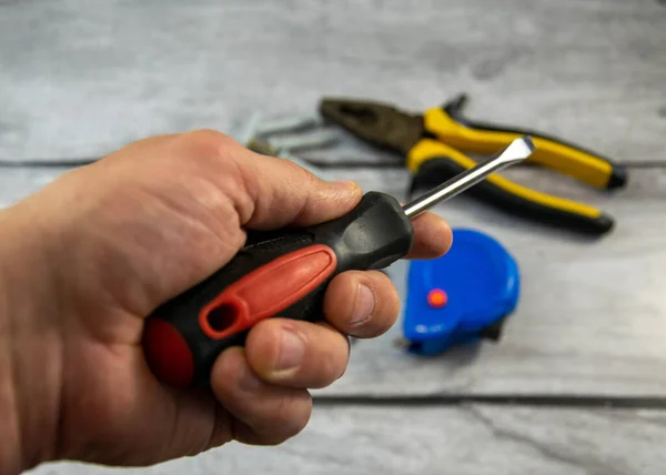 A black locksmith screwdriver in his hand on a gray background. — Stock Photo, Image