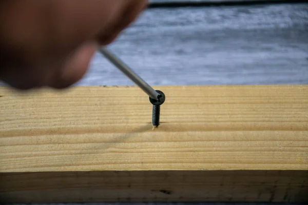 Screwing a self-tapping screw into a wooden bar. — Stock Photo, Image