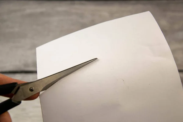 Kancelářské nůžky stříhají list papíru. — Stock fotografie