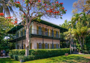 Key West, ABD - 04.30.2017: Ernest Hemingway Key West 'teki evi. Etrafında tropik bahçeler olan İspanyol kolonisi tarzında güzel, limon renkli bir villa. Veranda ve ahşap pencere perdeleri. Lüks ev.