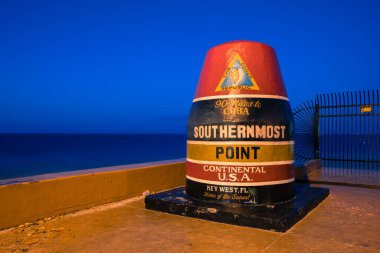 Key West, ABD - 04.17.2017: Çok erken saatlerde Key West, Florida 'da Birleşik Devletler kıtasının en güney noktasındaki renkli, boyalı şamandıra. Kıyıdaki mavi saat.