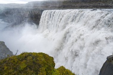 Avrupa 'nın en büyük şelalesi, Dettifoss. Çamurlu sular kenardan düşüyor. Yağmurlu ve bulutlu bir günde İzlanda Şelalesi.