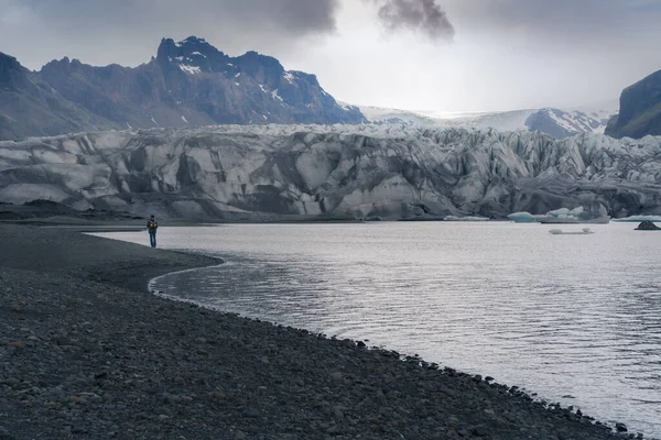アイスランド南部の寒い曇り空の日に氷河ラグーンで観光客が歩く 氷河は水の中に落ちる 厳しい 劇的な 霧の多い天気 — ストック写真