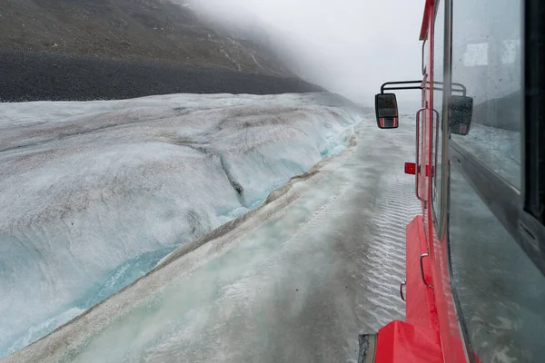雨の日にコロンビア氷河まで行く赤と白のオフロード観光バスからの眺め カナダのロッキー山脈の氷河の周りの寒い日 — ストック写真