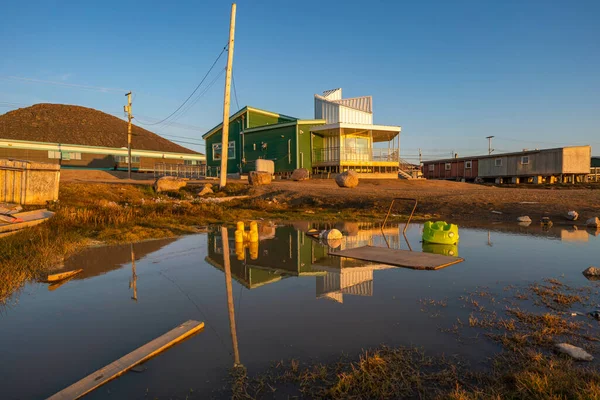 Golden hour in Inuit community of Qikiqtarjuaq, Broughton Island, Nunavut, Canada. Parks Canada building reflection on water surface. Settlement in the far north. Arctic community. The north.