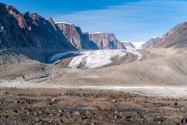 Sun shines above remote arctic valley of Akshayuk Pass, Baffin Island, Canada. Blue sky above Highway glacier. Arctic summer in the wild of the far north. Arctic wilderness.